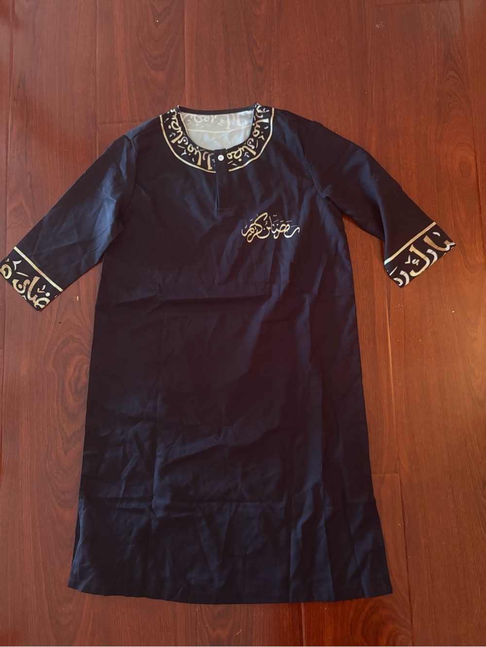 Brand new black and gold embroidered tobe with gold Arabic calligraphy on the be